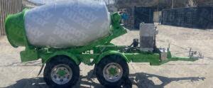 Portable concrete mixer with white drum and green frame featuring dual-axle trailer and Honda power system