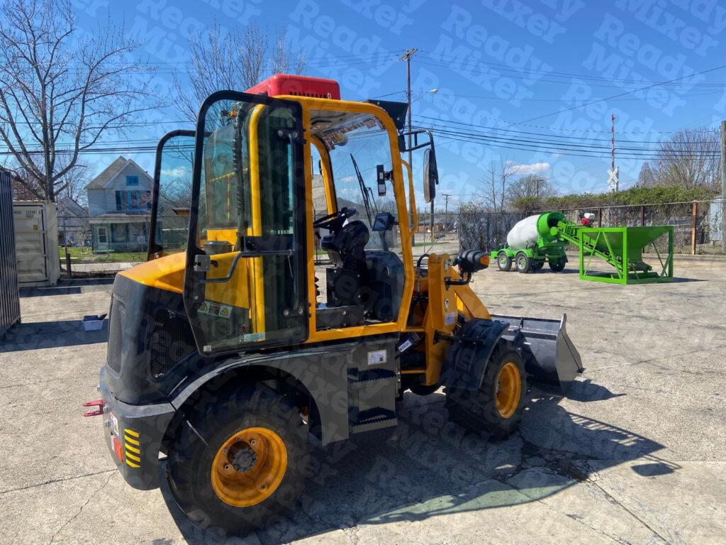 Yellow compact wheel loader displaying multiple attachments including material buckets and pallet forks