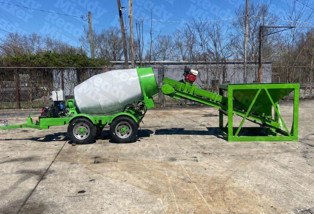 Portable 1-yard concrete mixer with green hopper system and tandem axle trailer setup