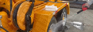 High-pressure water sprayer cleaning concrete mixer wheel, showing orange equipment maintenance in action