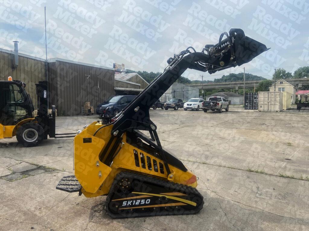 Yellow SK1250 mini tracked loader with extended black hydraulic arm on concrete surface