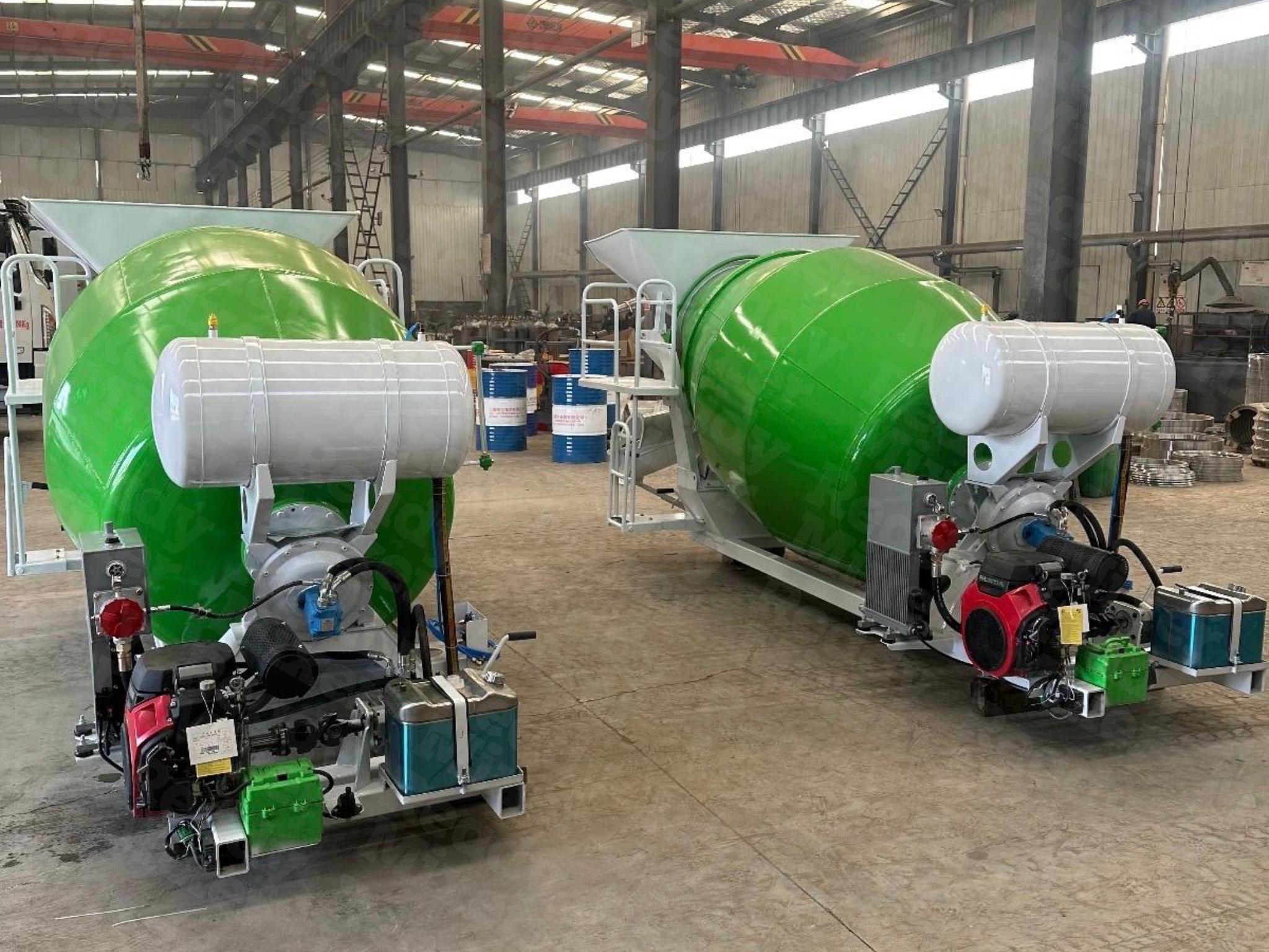 Two green Ready Mixer concrete mixers with white fuel tanks and Honda engines mounted on skid rail systems