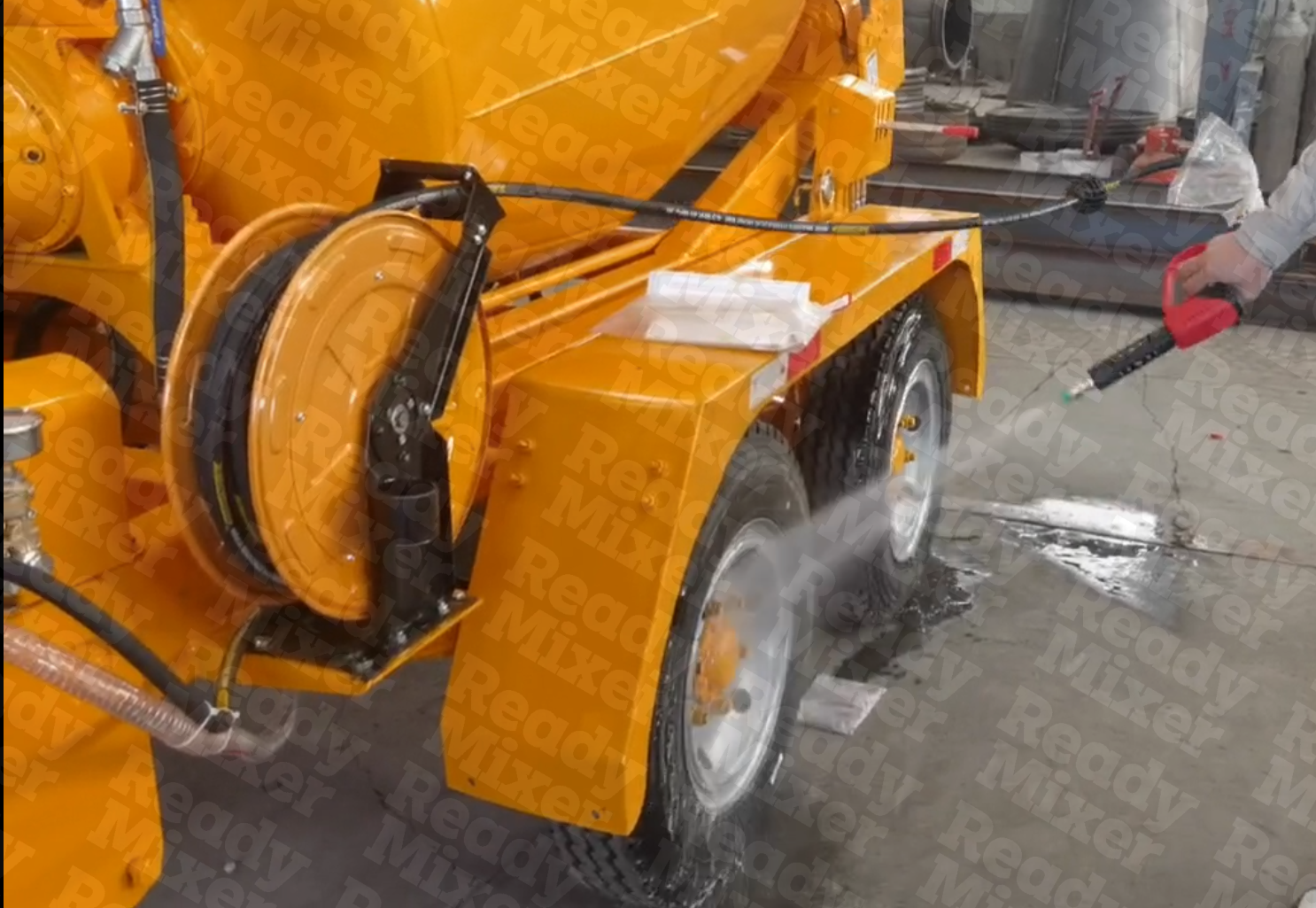 Orange Ready Mixer water sprayer attachment with black hose reel being serviced in workshop