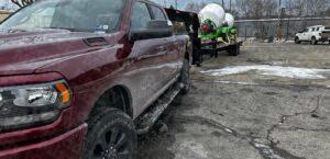 Pickup truck hauling Ready Mixer concrete equipment on black gooseneck trailer in winter conditions