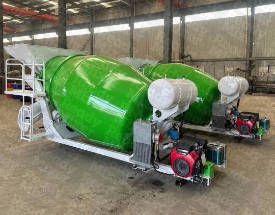 Side view of green 3-yard portable concrete mixers with white drums and Honda engines on manufacturing floor